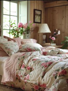 a bed with pink flowers on it in a room next to a lamp and window