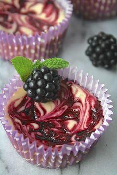 some cupcakes with berries and cream on them are sitting on a marble surface