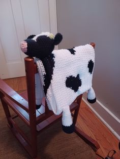 a stuffed cow sitting on top of a wooden rocking chair