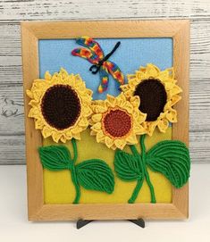 an embroidered picture frame with sunflowers and a dragonfly on the back side