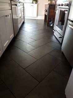 a kitchen with black tile floors and white cabinets