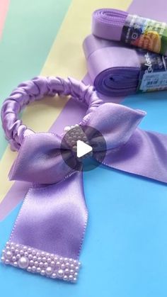 a purple ribbon with pearls on it next to a tube of toothpaste and a roll of crayons