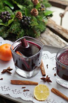 two glasses filled with liquid sitting on top of a table next to an orange and cinnamon stick