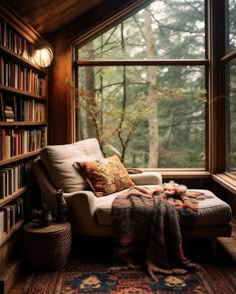 a room with a chair, bookshelf and rug in front of the window