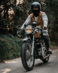 a man riding on the back of a motorcycle down a road