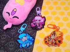 two keychains with cartoon characters on them next to a stuffed animal and other items