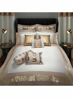 a bed with white and gold comforters on top of it