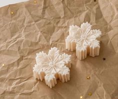 two snowflake shaped soaps sitting on top of brown paper