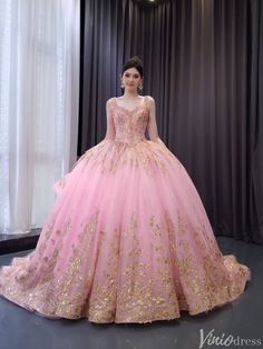 a woman in a pink and gold ball gown standing next to a window with curtains