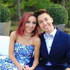 a young man and woman sitting next to each other on a white bench smiling at the camera