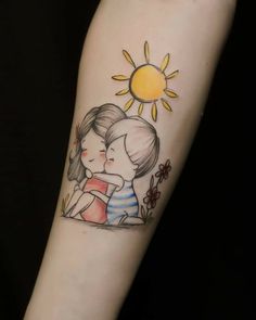 a woman's arm with a drawing of two people hugging and the sun behind her