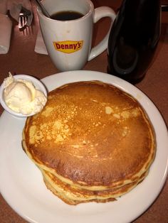 a stack of pancakes sitting on top of a white plate next to a cup of coffee