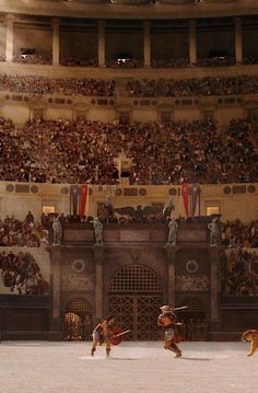 two men on horses in front of an arena full of people and dogs with swords