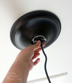 a hand is plugged in to a ceiling fan with a black light bulb on it