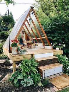 a small house made out of wood and glass in the middle of a garden with steps leading up to it