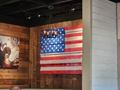 an american flag is hanging on the wall next to a wooden paneled room with pictures