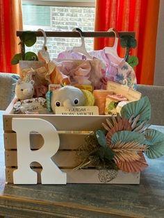 a wooden crate filled with baby's items on top of a table next to a window