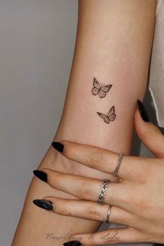 two women's hands with matching tattoos on their fingers and one has a butterfly tattoo on her left arm