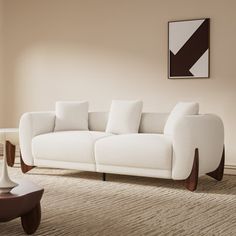 a white couch sitting in a living room on top of a carpeted floor next to a table