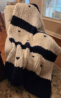 two knitted blankets sitting on top of a chair in a living room next to a window