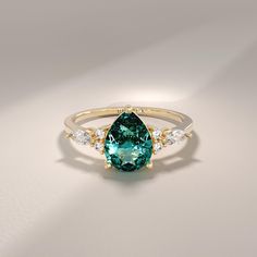 a green and white stone ring with three diamonds on the side, set in yellow gold