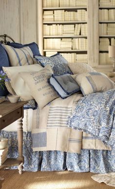 a bed with blue and white comforters in front of a bookcase filled with books