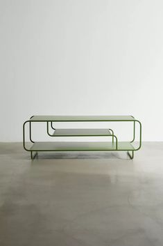 a green coffee table sitting on top of a cement floor next to a white wall