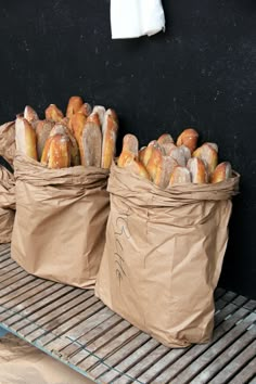 two bags filled with bread sitting on top of a conveyor belt in front of a black wall