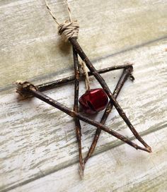 a star ornament made out of sticks with a red glass bottle in the middle