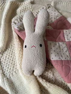 a stuffed rabbit laying on top of a blanket next to a pillow and combs