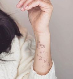 a woman's arm with a small star and moon tattoo on her left wrist