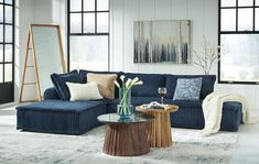 a living room with blue couches and coffee table in front of large open windows