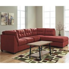 a red sectional couch sitting on top of a wooden floor next to a coffee table