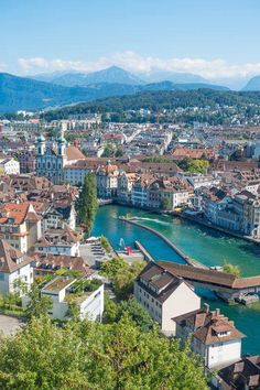 an aerial view of a river running through a city with mountains in the back ground