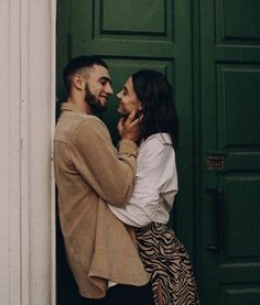 a man and woman standing next to each other in front of a green door together