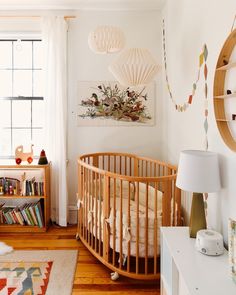 a baby's room with a crib, bookshelf, and window