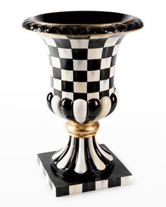 a black and white checkerboard vase with gold trimmings on the base