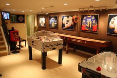 a game room with two foo - o - mat tables and several video screens on the wall