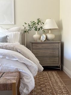 a bed with white linens and pillows in a bedroom next to a wooden dresser