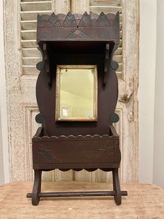 an old fashioned mirror sitting on top of a wooden stand