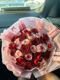 a woman holding a bouquet of roses in her lap with candles and cherries on it