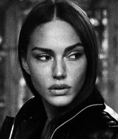 a black and white photo of a woman with dark hair, wearing a leather jacket