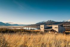 a house in the middle of a field with mountains in the background