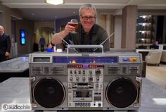 a man is drinking from a glass next to an old radio