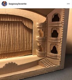 a cardboard model of a stage set with curtains and steps on the side, in front of a window