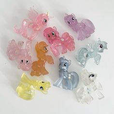 a group of small plastic pony toys sitting on top of a white table next to each other