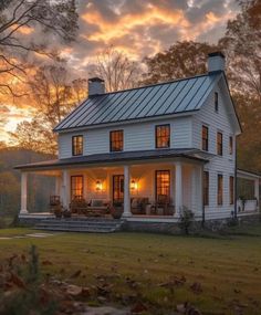 a white house sitting on top of a lush green field under a cloudy sky at sunset