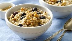 two white bowls filled with oatmeal and nuts on top of a blue cloth