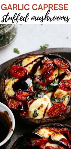 garlic caprese stuffed mushrooms with tomatoes and basil on a serving platter next to a cup of coffee