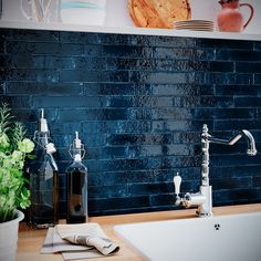 a kitchen sink with soap dispenser and bottles on the counter top next to it